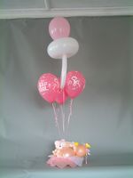 baby girl in basket with bouquet balloons